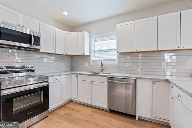 kitchen featuring sink, white cabinetry, stainless steel appliances, and light hardwood / wood-style flooring