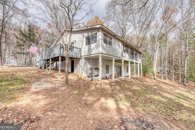 back of house featuring a sunroom, a patio area, and a wooden deck