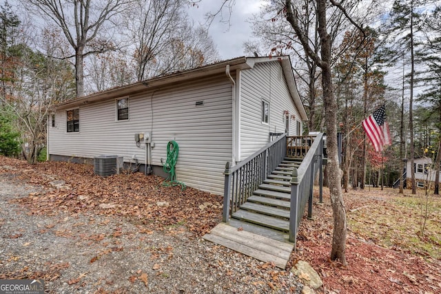 view of side of home with central air condition unit and a wooden deck