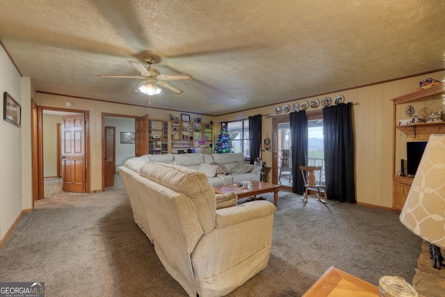 carpeted living room featuring ceiling fan, wooden walls, crown molding, and a textured ceiling