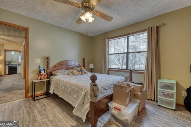 bedroom with ceiling fan, light hardwood / wood-style flooring, and a textured ceiling