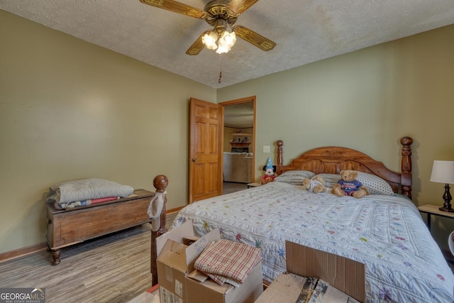 bedroom featuring ceiling fan, light hardwood / wood-style flooring, and a textured ceiling