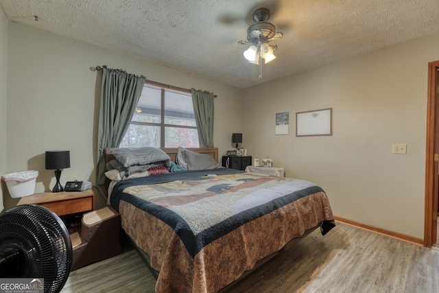 bedroom with ceiling fan, a textured ceiling, and hardwood / wood-style flooring