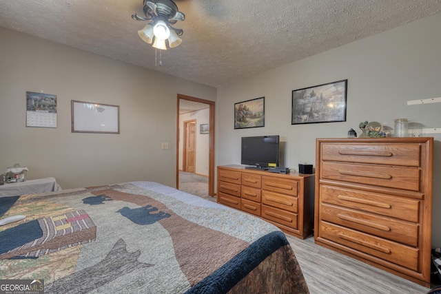 bedroom with a textured ceiling, light hardwood / wood-style floors, and ceiling fan