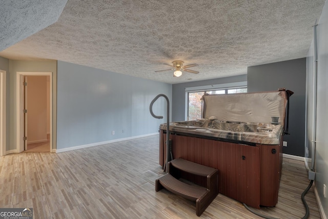 kitchen featuring ceiling fan, light wood-type flooring, and a textured ceiling