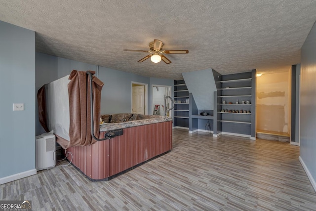 interior space with ceiling fan, a textured ceiling, and light wood-type flooring