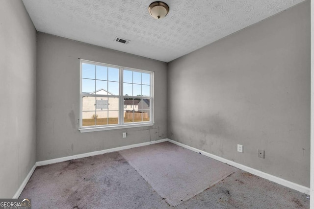 empty room with carpet flooring and a textured ceiling