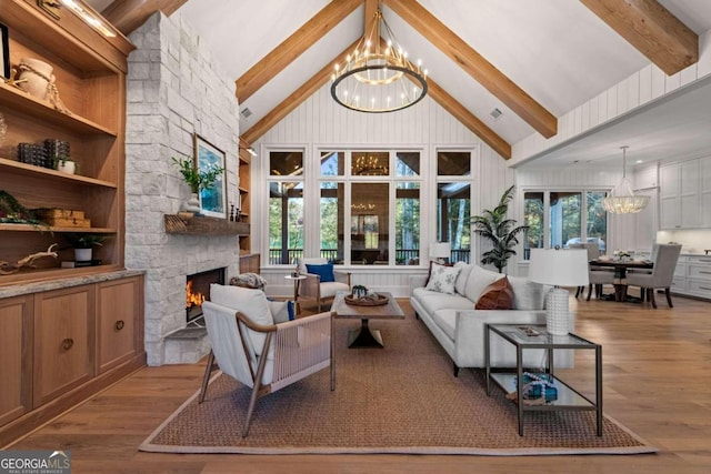 living room with light wood-type flooring, a fireplace, a wealth of natural light, and a chandelier