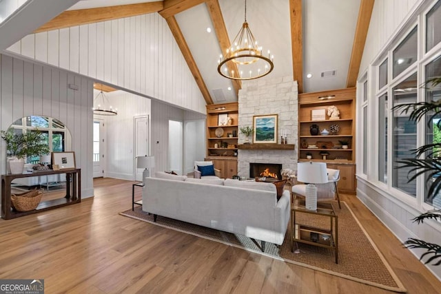 living room with high vaulted ceiling, built in features, beam ceiling, and a fireplace