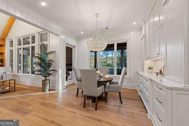 dining room with crown molding, an inviting chandelier, and light hardwood / wood-style floors