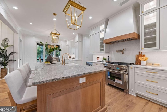 kitchen with custom exhaust hood, white cabinetry, and high end stainless steel range