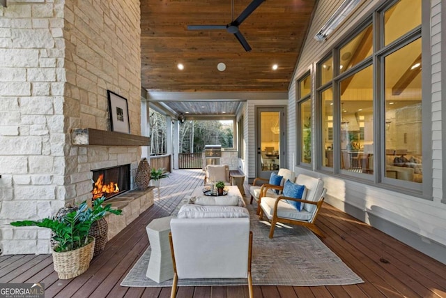 wooden terrace featuring ceiling fan and an outdoor living space with a fireplace