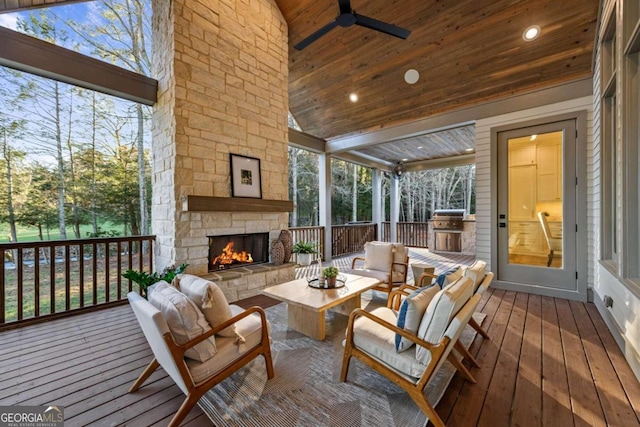 sunroom / solarium featuring lofted ceiling, ceiling fan, wood ceiling, and an outdoor stone fireplace