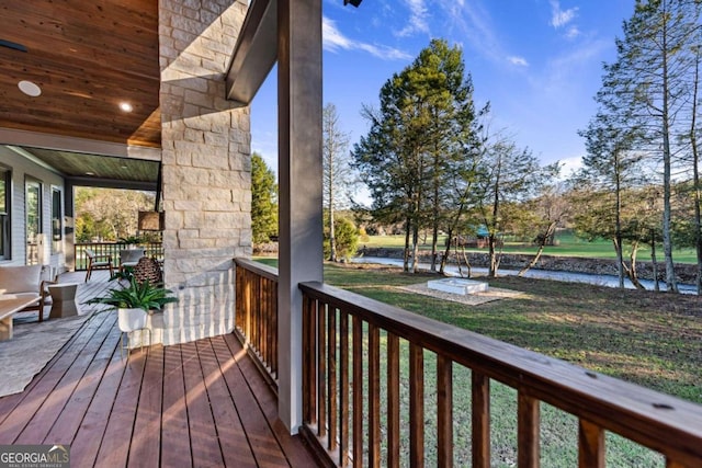 wooden deck featuring a water view and a lawn