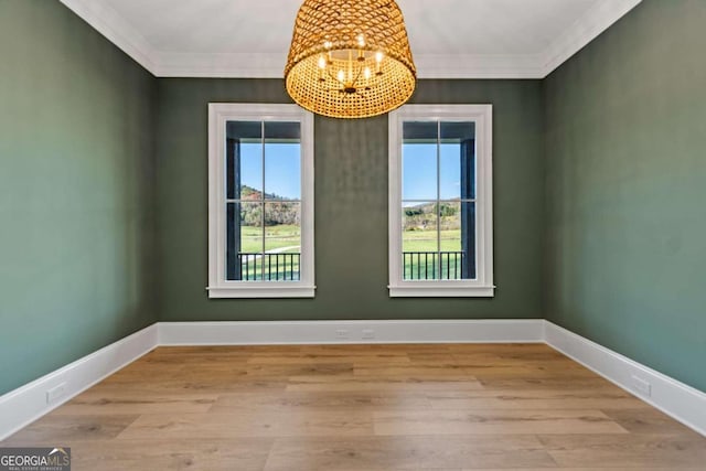 empty room with ornamental molding, a notable chandelier, and light wood-type flooring