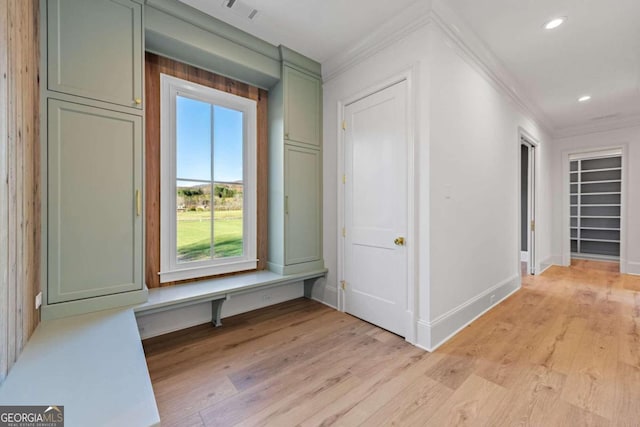 hall with light hardwood / wood-style floors and crown molding