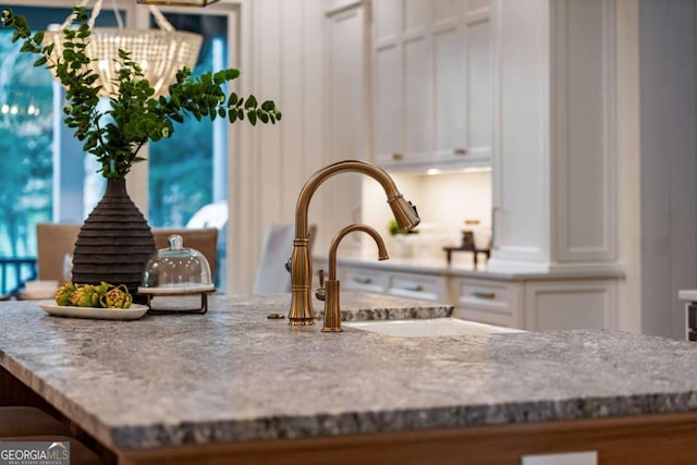 details featuring white cabinetry and light stone counters