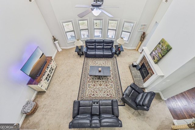 living room featuring a high ceiling, a brick fireplace, plenty of natural light, and ceiling fan