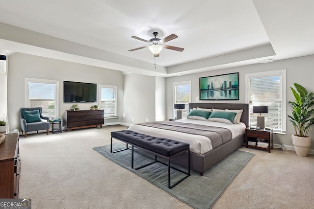 carpeted bedroom featuring a tray ceiling and ceiling fan