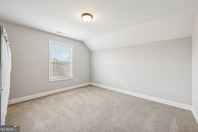 additional living space with light colored carpet and vaulted ceiling