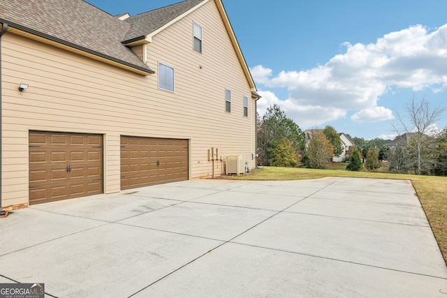 view of side of property featuring a yard, central AC unit, and a garage