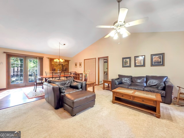 carpeted living room with ceiling fan with notable chandelier and vaulted ceiling