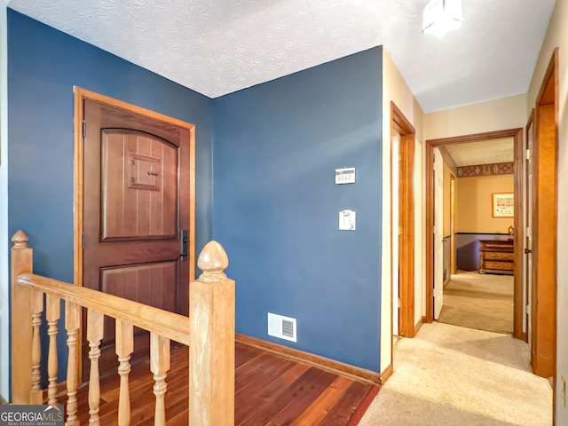 foyer entrance with a textured ceiling and carpet floors