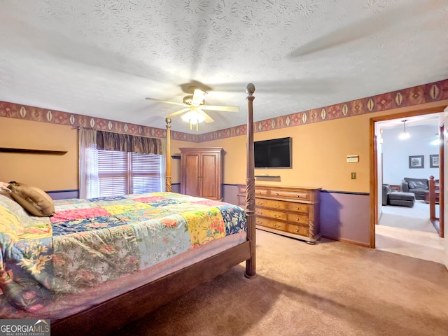 bedroom with a textured ceiling, light colored carpet, and ceiling fan