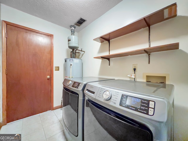 laundry area with independent washer and dryer, a textured ceiling, gas water heater, and light tile patterned floors