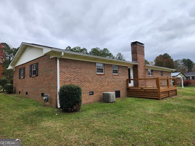 rear view of house featuring a deck, a yard, and central AC