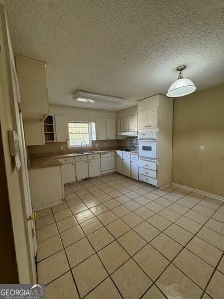 kitchen featuring white cabinetry, light tile patterned floors, oven, and a textured ceiling