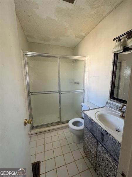 bathroom with tile patterned floors, vanity, a textured ceiling, and walk in shower