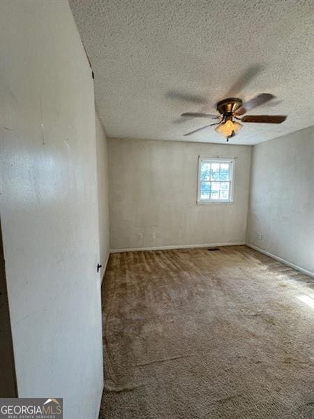 carpeted empty room featuring ceiling fan and a textured ceiling