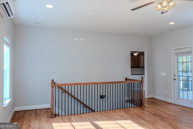 spare room with an AC wall unit, a wealth of natural light, and light hardwood / wood-style floors