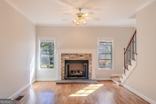 unfurnished living room featuring ceiling fan, light hardwood / wood-style floors, ornamental molding, and a fireplace