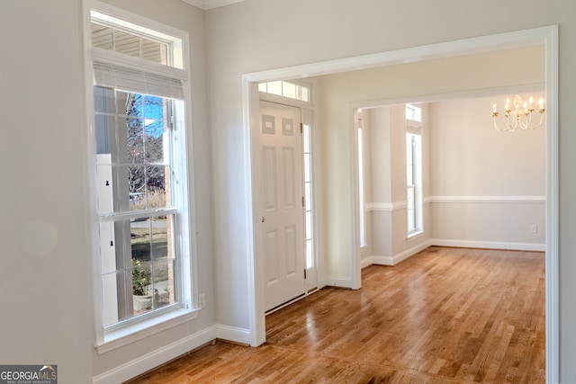 entryway featuring ornamental molding, hardwood / wood-style flooring, a healthy amount of sunlight, and a notable chandelier