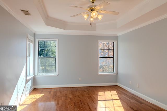 unfurnished room featuring a tray ceiling, crown molding, and light hardwood / wood-style floors