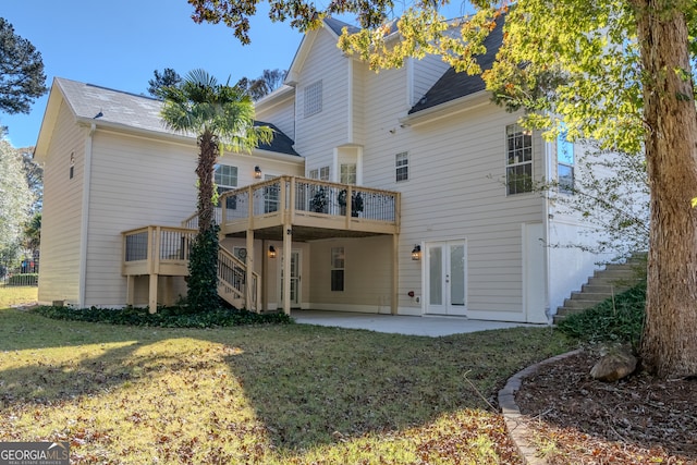 rear view of property with a lawn, a wooden deck, and a patio