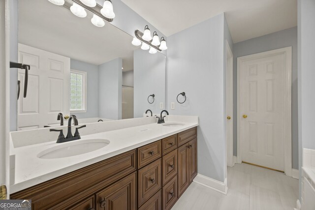 bathroom with double vanity, a sink, and a tub