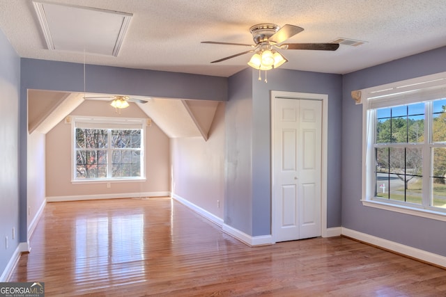 additional living space with ceiling fan, a textured ceiling, and light wood-type flooring