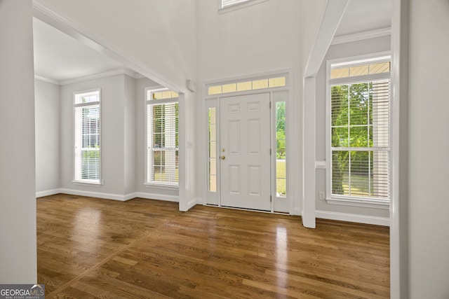 entrance foyer with crown molding, baseboards, and wood finished floors