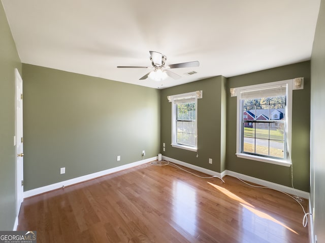 empty room with wood-type flooring, a wealth of natural light, and ceiling fan