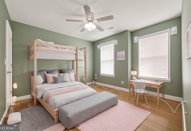bedroom featuring baseboards, a ceiling fan, wood finished floors, and visible vents