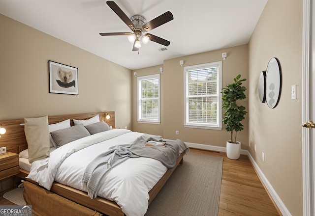 bedroom with baseboards, a ceiling fan, light wood-type flooring, and visible vents