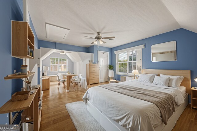 bedroom with ceiling fan, vaulted ceiling, multiple windows, and wood finished floors