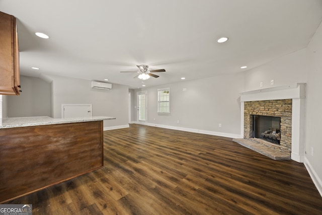unfurnished living room with a ceiling fan, baseboards, a fireplace with raised hearth, dark wood-style floors, and recessed lighting