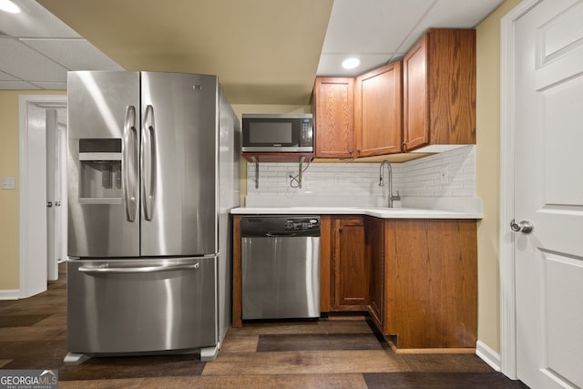 kitchen with light countertops, backsplash, stainless steel appliances, and brown cabinets