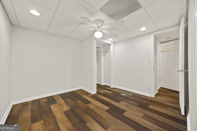 basement featuring a ceiling fan, baseboards, dark wood-style floors, a drop ceiling, and recessed lighting