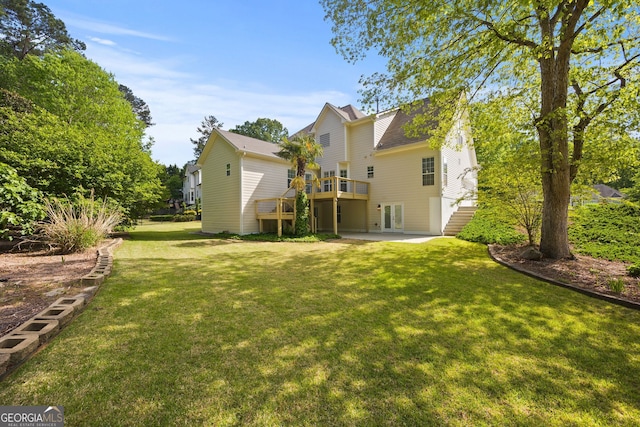 rear view of property featuring a lawn, a patio area, a wooden deck, and stairway