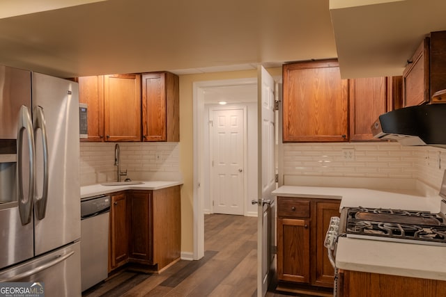 kitchen featuring dark hardwood / wood-style flooring, tasteful backsplash, ventilation hood, stainless steel appliances, and sink